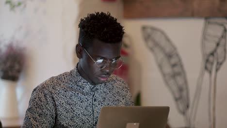 Focused-African-American-freelancer-using-laptop-in-cafe